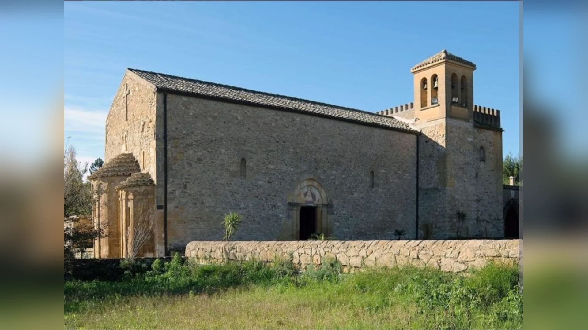 L'Abbazia di Santo Spirito a Caltanissetta vista da fuori: la lunga navata in pietra, il campanile merlato e il prato verde davanti
